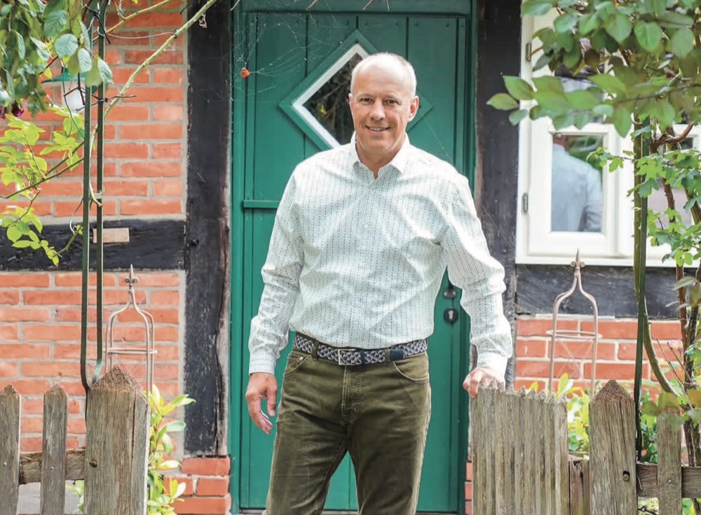 Dietmar Fischer an einem Gartentor vor einem Fachwerkhaus
