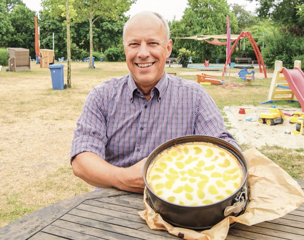 Dietmar Fischer sitzend mit einem frisch gebackenen Kuchen in den Händen